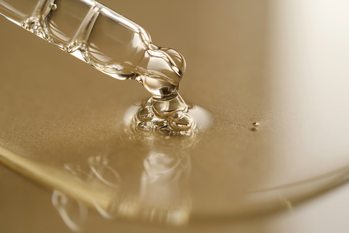 Pipettes with Oil or Serum on a Golden Background.